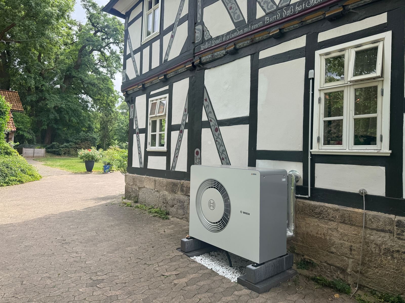 Bosch-Wärmepumpe vor einem Fachwerkhaus mit Sandsteinsockel