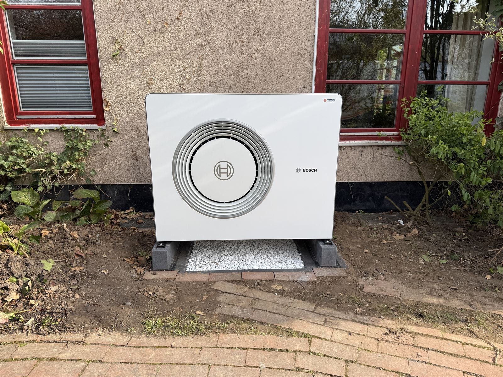 Bosch-Wärmepumpe vor einem Mehrfamilienhaus mit roten Fenstern in Kassel