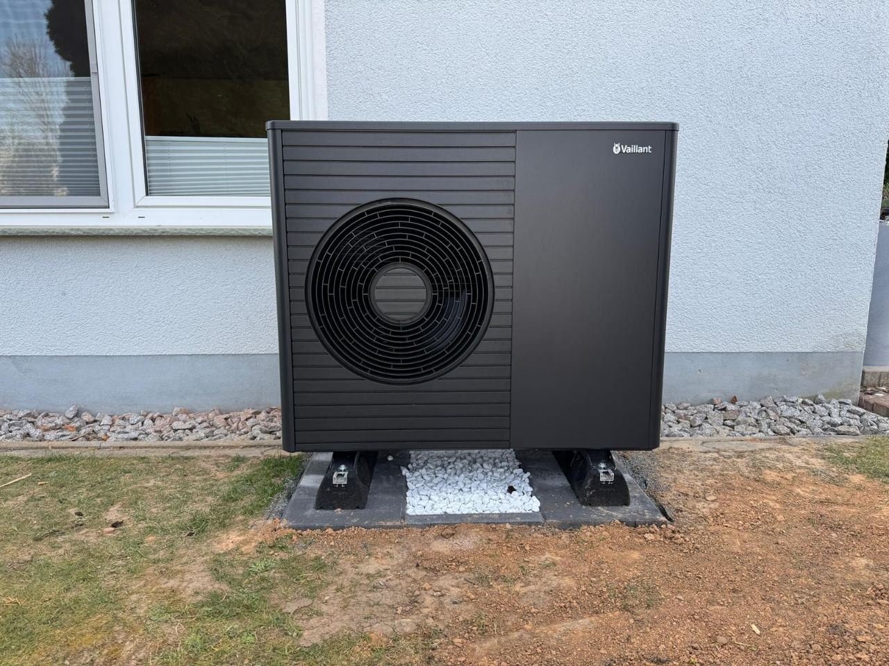 Schwarzes Vaillant-Außengerät auf Kiesbett vor einer weißen Hauswand