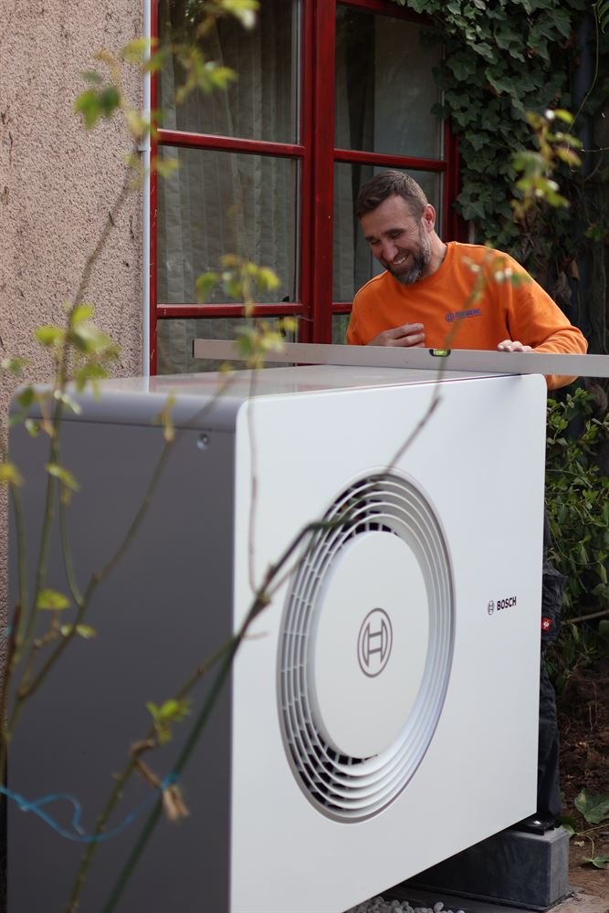 Monteur richtet eine Bosch-Wärmepumpe mit der Wasserwaage aus