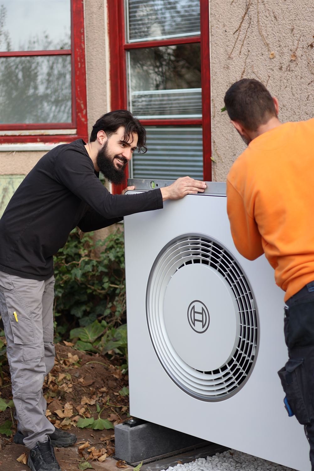 Harun Merdic und ein Monteur richten gemeinsam eine Bosch-Wärmepumpe aus